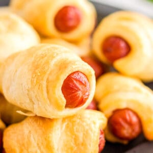 Close up image of finished Pigs in a Blanket stacked on a black plate.