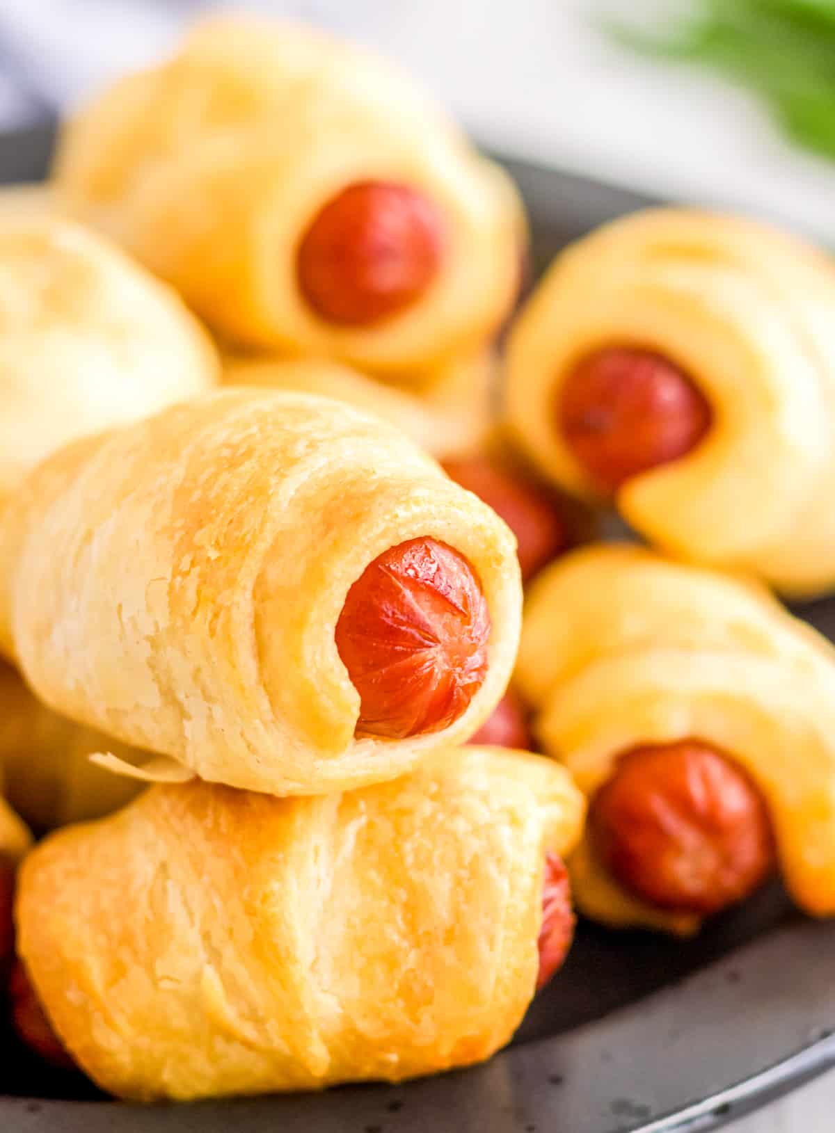 Stacked Air Fryer Pigs in a Blanket on black plate.