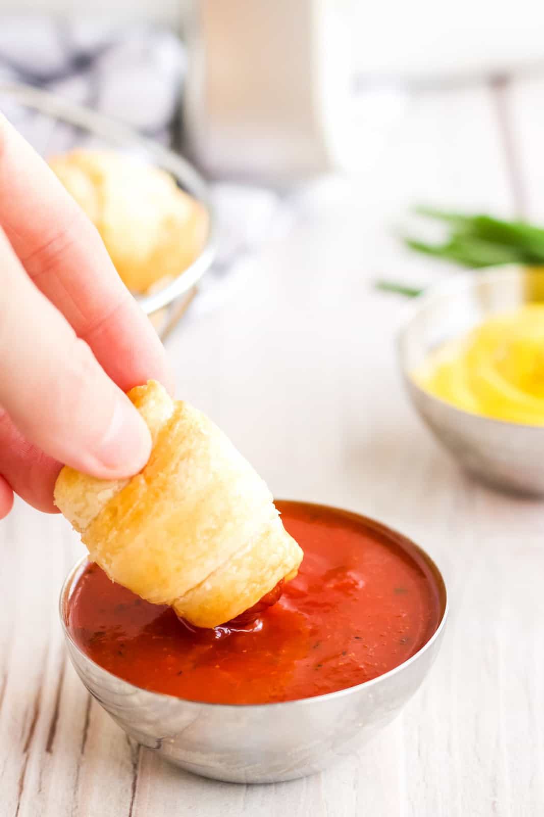 Hand dipping one Air Fryer Pigs in a Blanket in ketchup