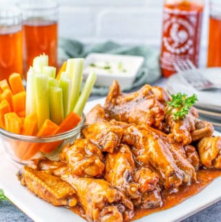 Slow Cooker Chicken Wings on white plate with celery and carrot sticks
