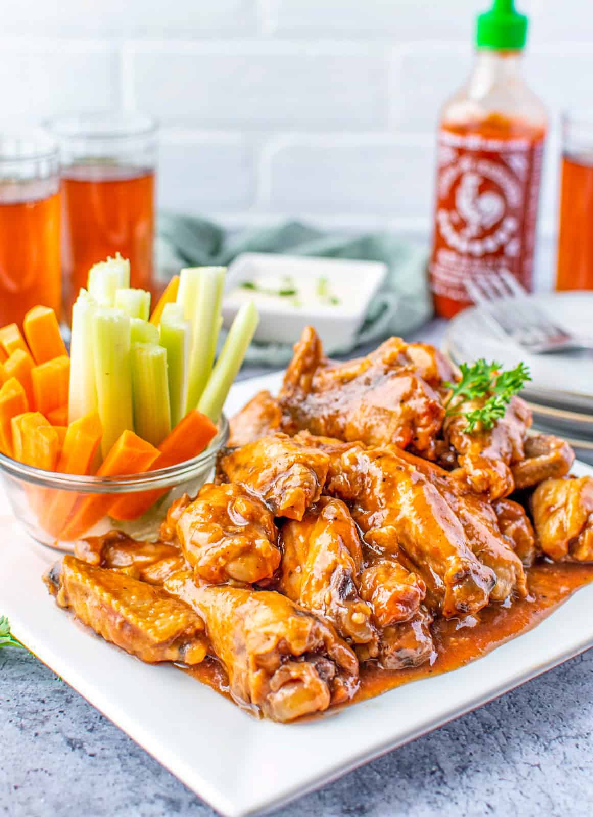 Slow Cooker Chicken Wings on white plate with celery and carrot sticks