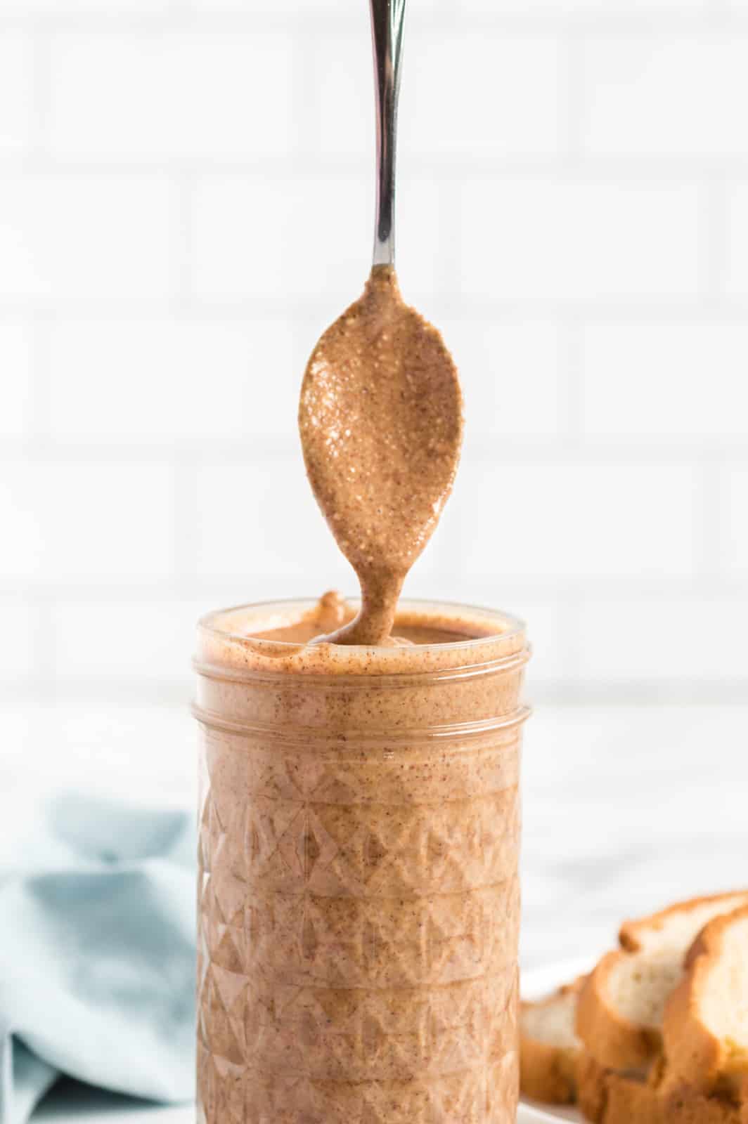 Spoon showing almond butter in jar pulling up