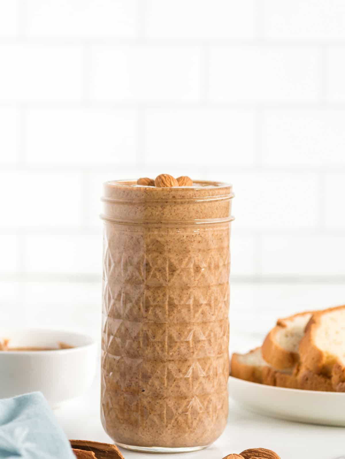Side view of Cinnamon Almond Butter in jar topped with almonds