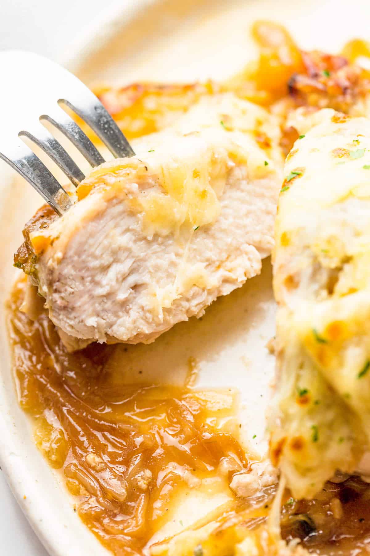 Close up of a cut piece of chicken with fork holding it open.