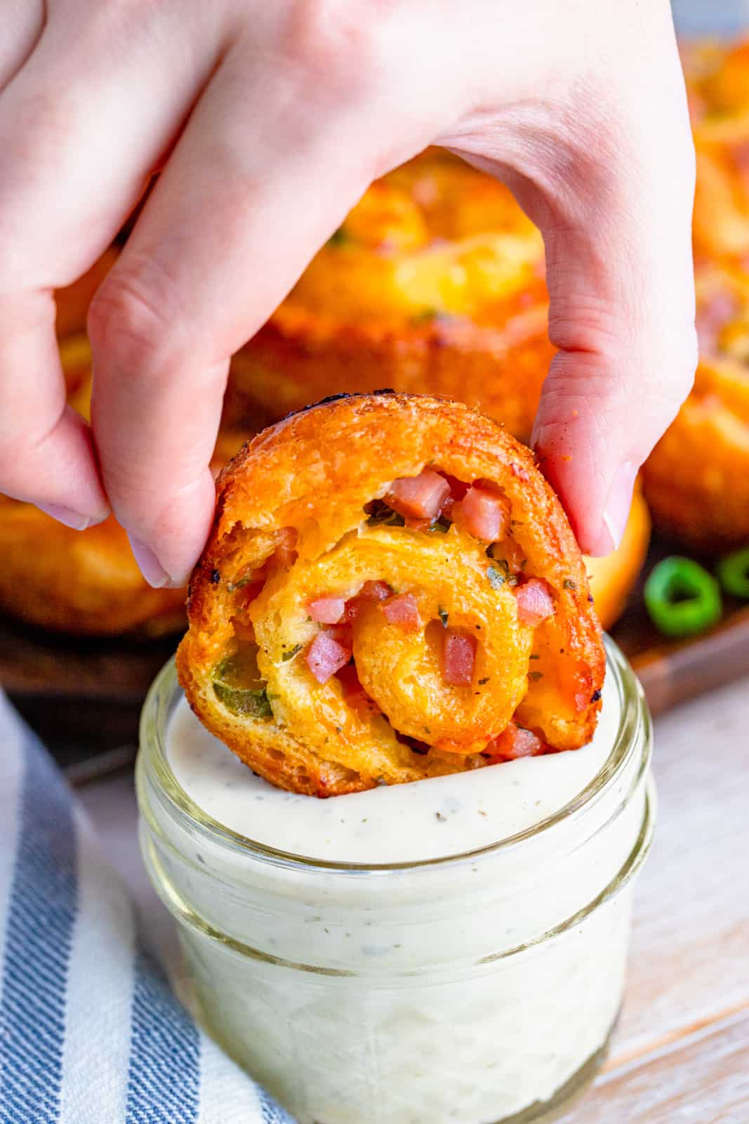 Hand dipping one Ranch Ham and Cheese Pinwheel into ranch