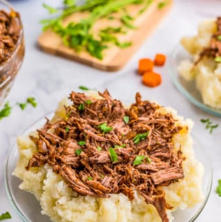 Close up of Slow Cooker Beef Short Ribs over mashed potatoes topped with parsley