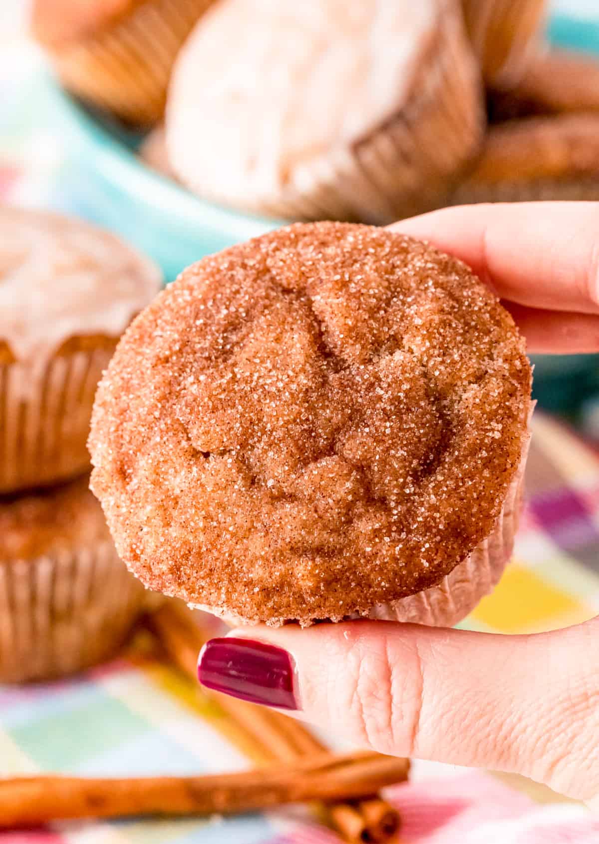Hand holding up one muffin showing the cinnamon sugar topping.