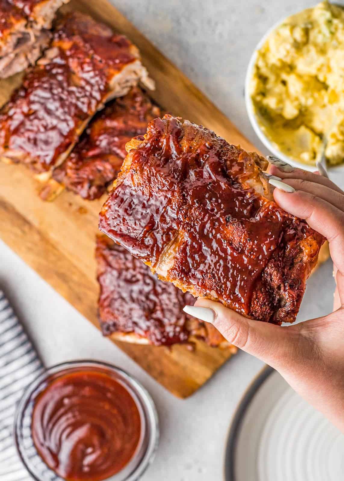 Hand holding up one portion of Instant Pot BBQ Ribs