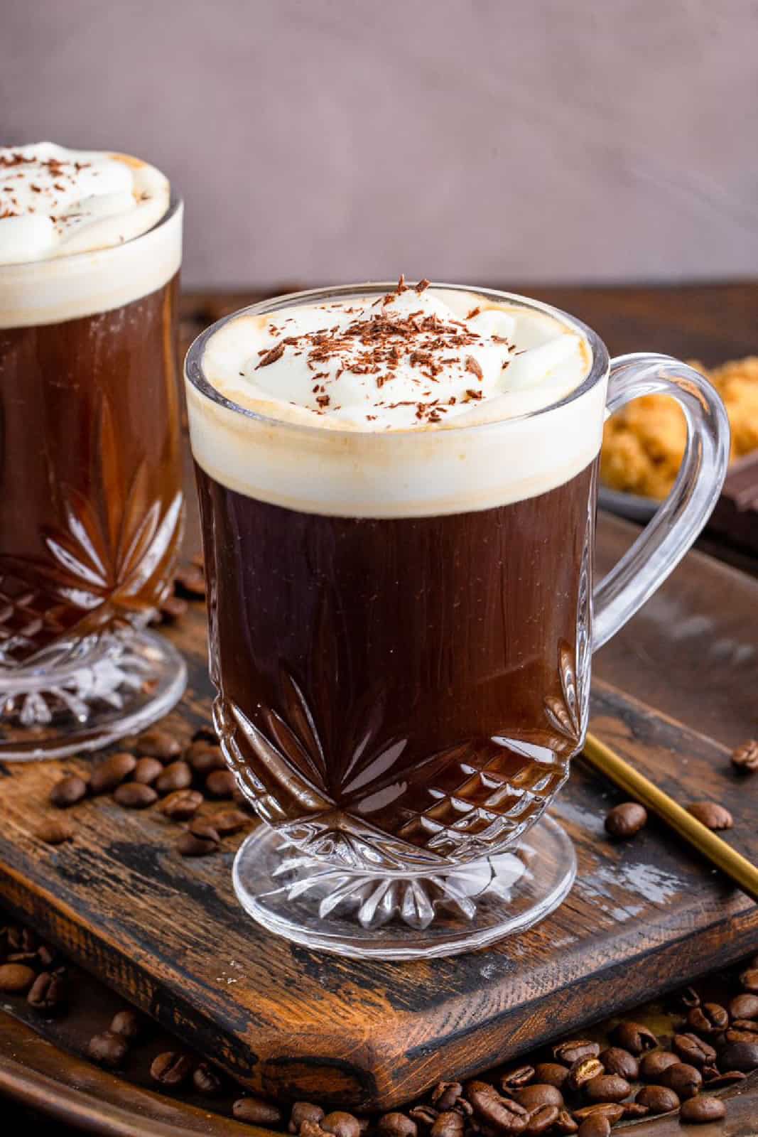 Close up of two mugs of Irish Coffee Recipe on wooden tray with coffee beans