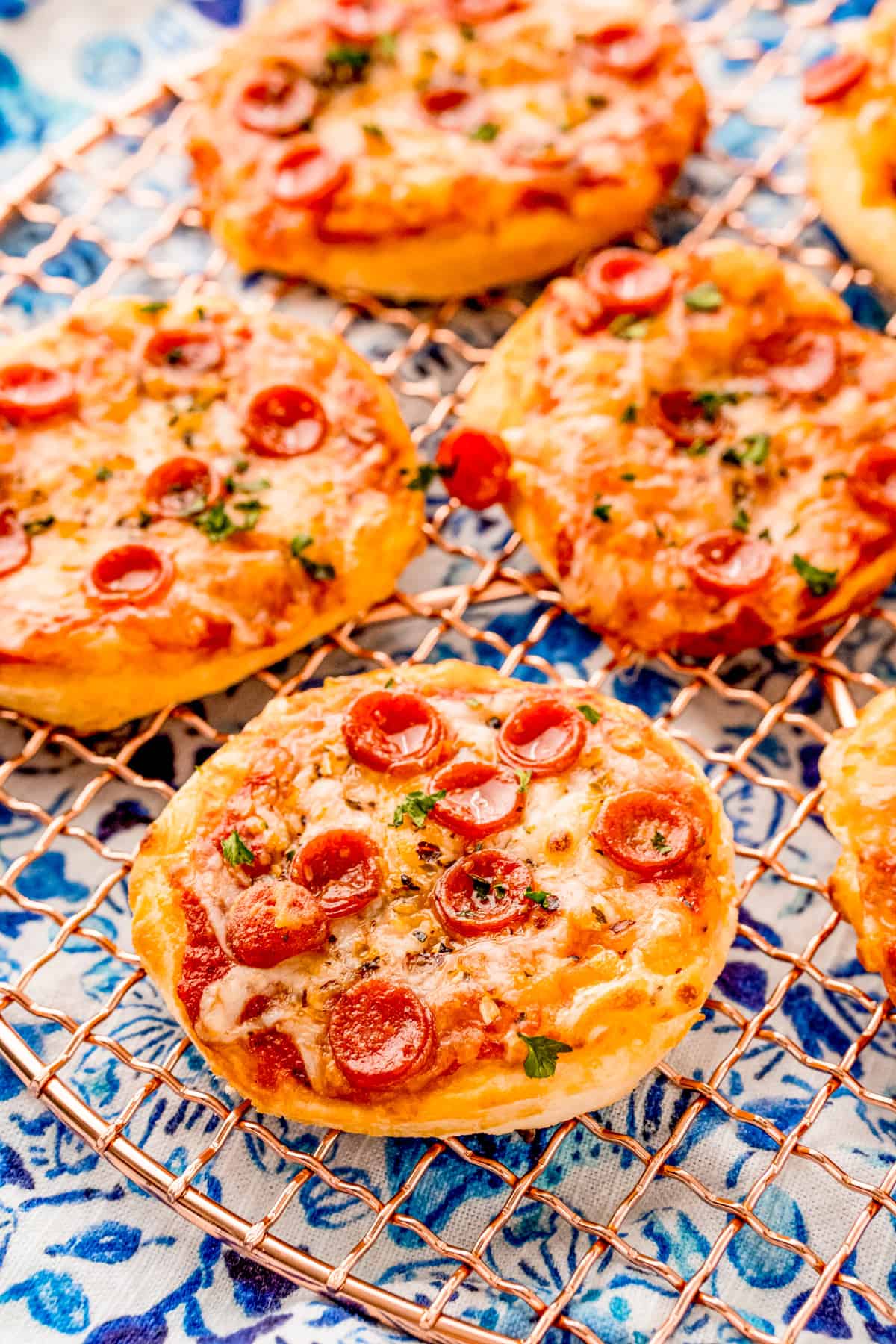 Finished Mini Air Fryer Pizza recipe on round cooling rack showing the toppings.