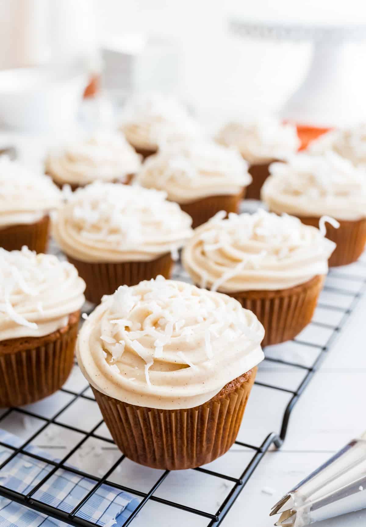 Carrot Cake Cupcakes on wire rack frosted and topped with coconut.