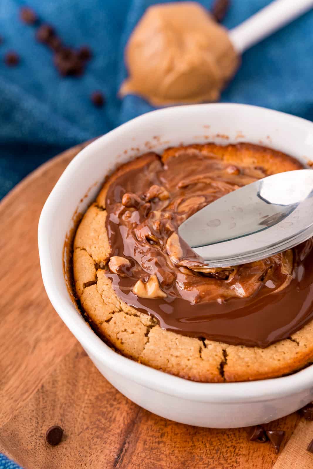 Spoon spreading out melted peanut butter and chocolate over Baked Oats