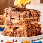 Side view of three Cheesecake Bars drizzled with chocolate syrup square image