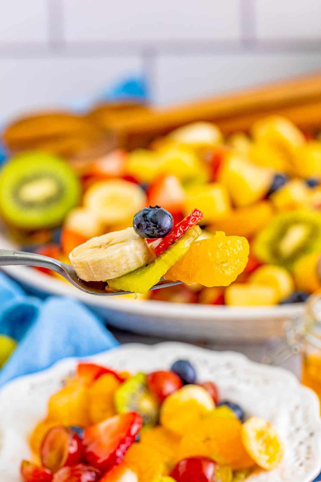 Spoon holding up a bite of fruit salad.