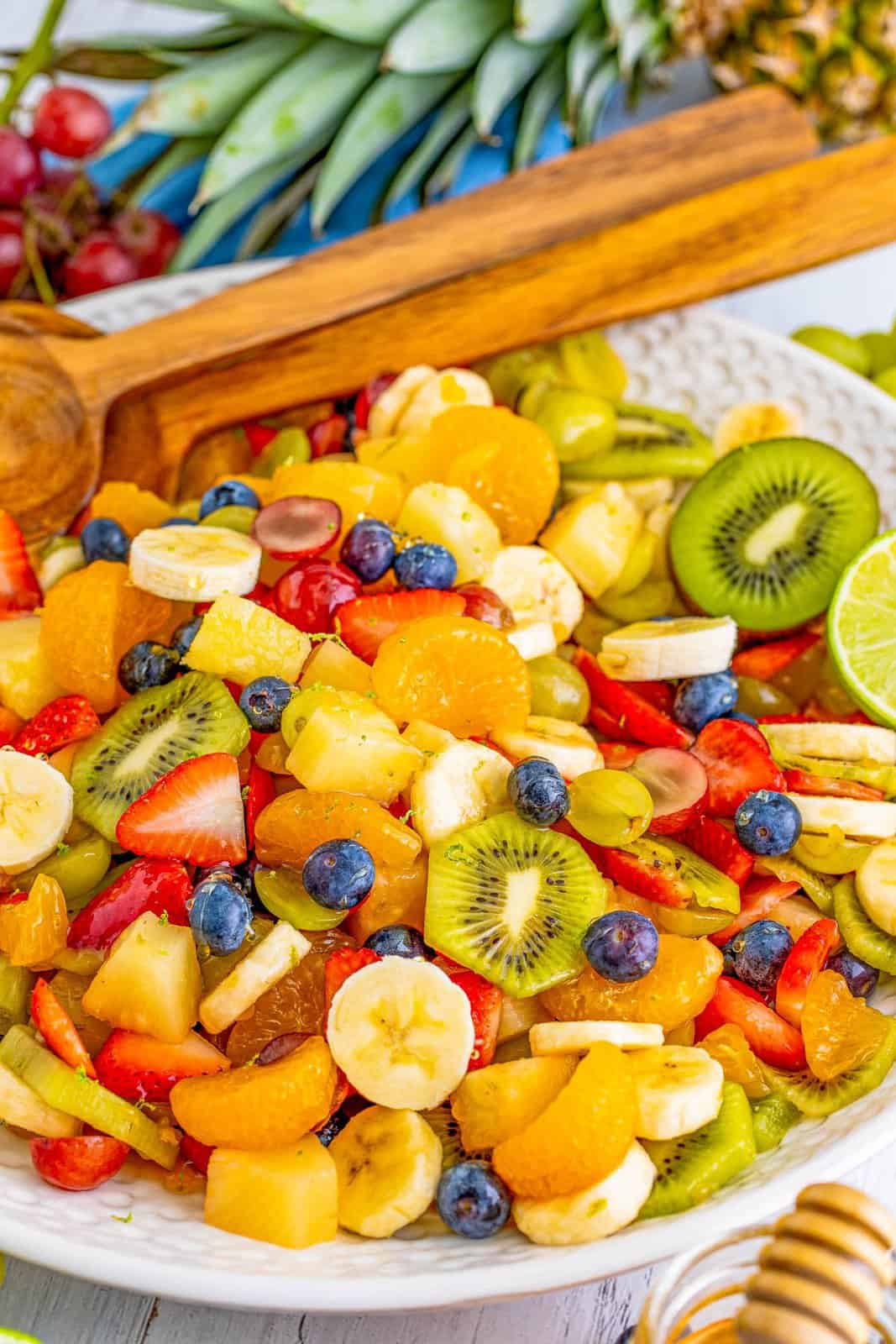 Fruit Salad Recipe in large serving bowl with wooden spoons.