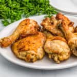 Close up photo of Air Fryer Chicken on white plate with parsley in background