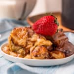 Air Fryer Cinnamon Roll Casserole on white plate topped with strawberry square image