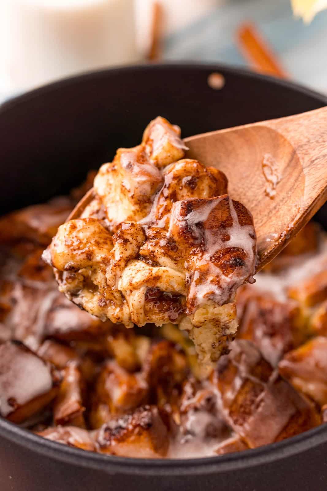 Wooden spoon scooping some Cinnamon Roll Casserole out of baking pan