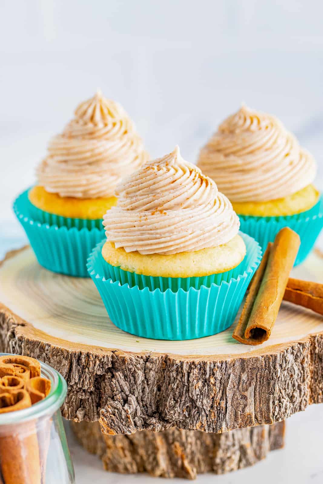 Three cupcakes on wooden round topped with frosting