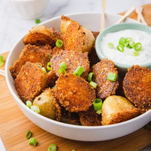 Square photo of Crispy Parmesan Potato Recipe in bowl with dipping sauce and green onions and dipping sauce