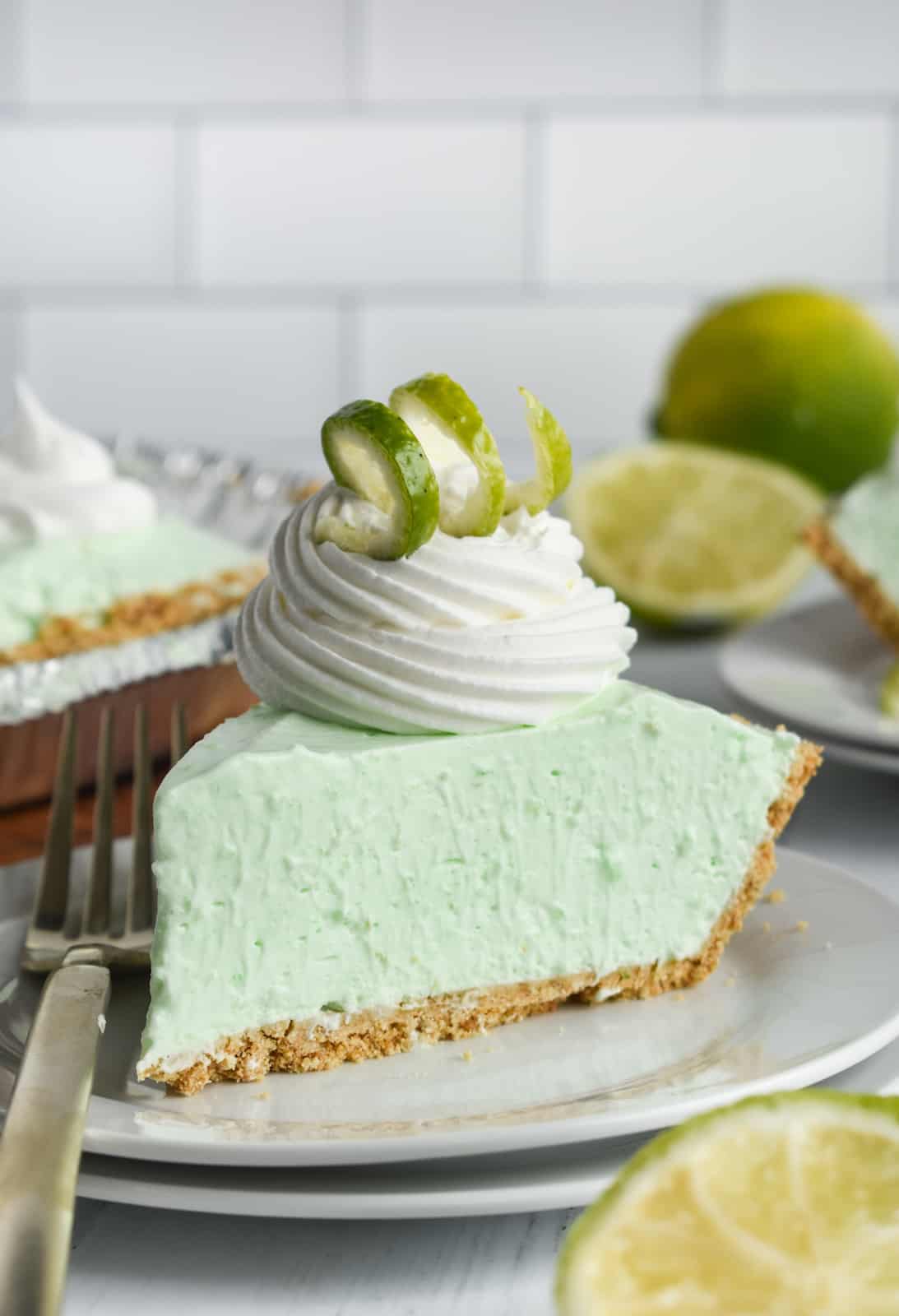 Slice of Jello Pie on white plate with whipped cream a lime zest swirl