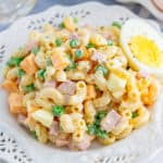 Square image of Macaroni Salad on white plate with egg