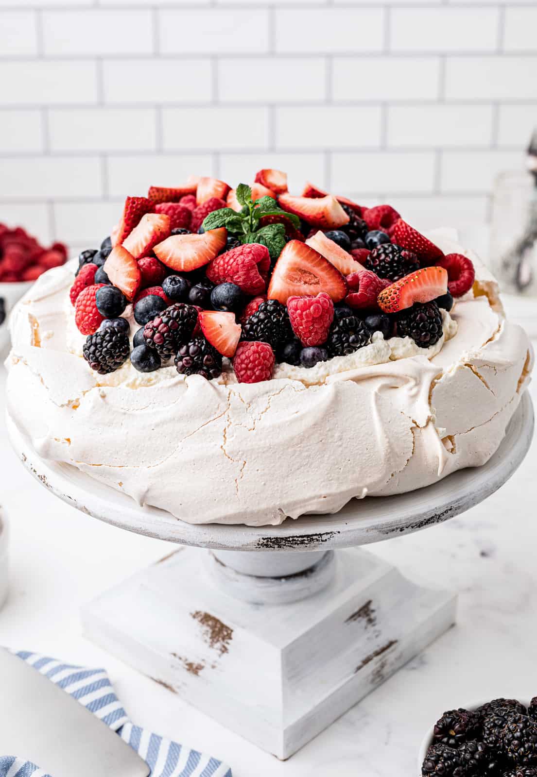 Finished Pavlova Recipe topped with whipped cream and mixed berries