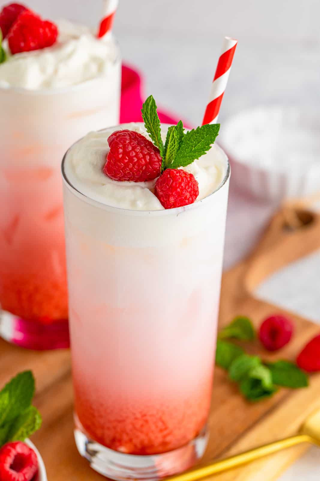 Close up of one Italian Soda garnished with raspberries, mint and straw