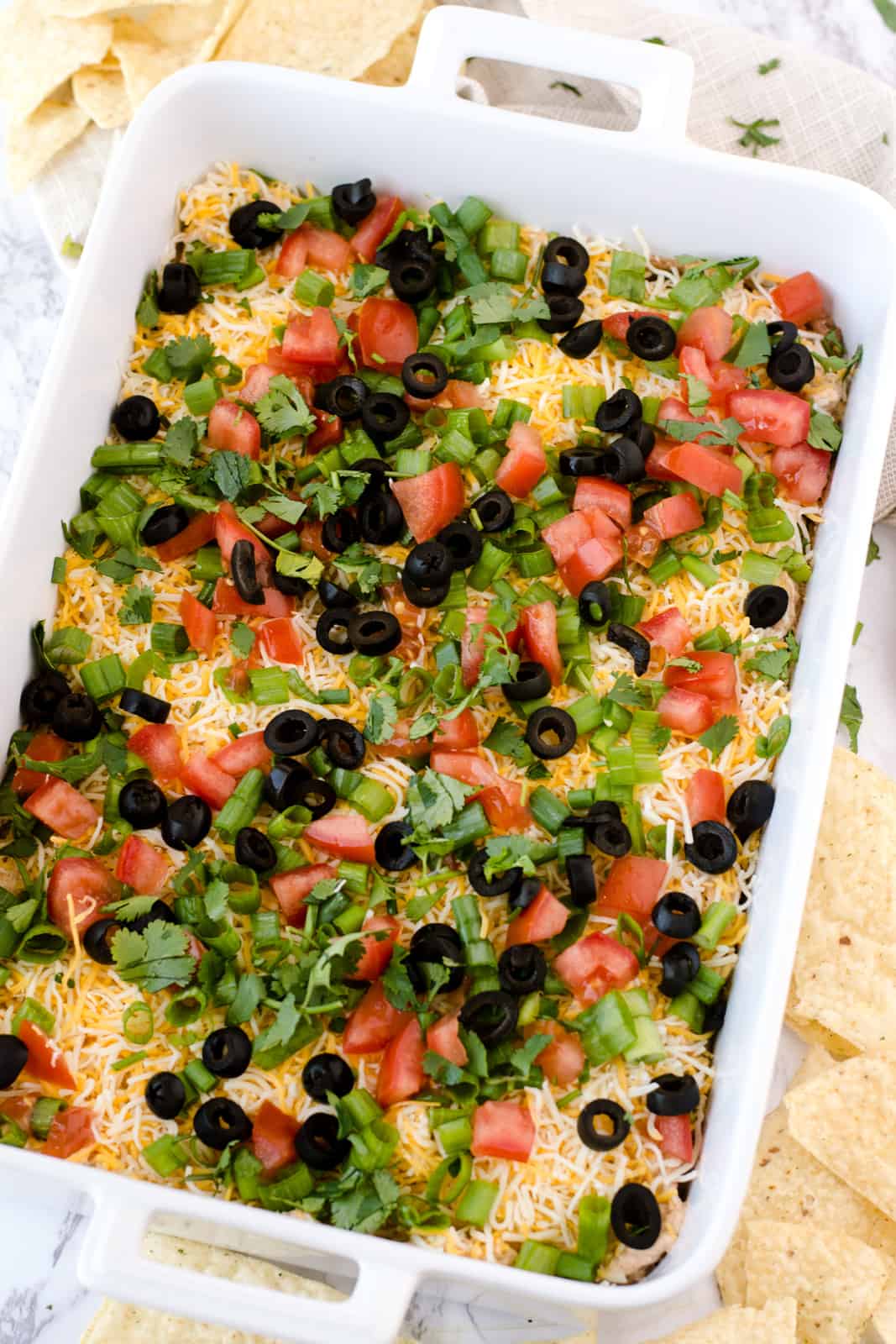 Overhead of finished 7 Layer Dip in white dish with chips