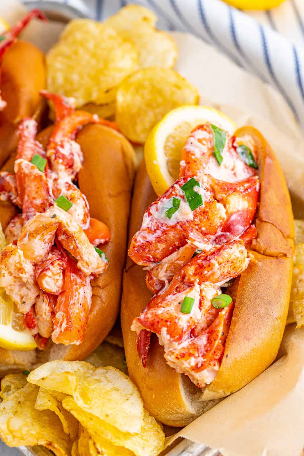 Two Lobster Rolls on tray with chips and lemon