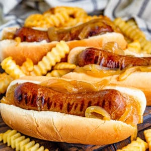 Square image of 3 brats in buns with French fries