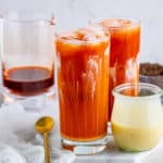 Square photo of two glasses of Thai Iced Tea with spoon and sweetened condensed milk
