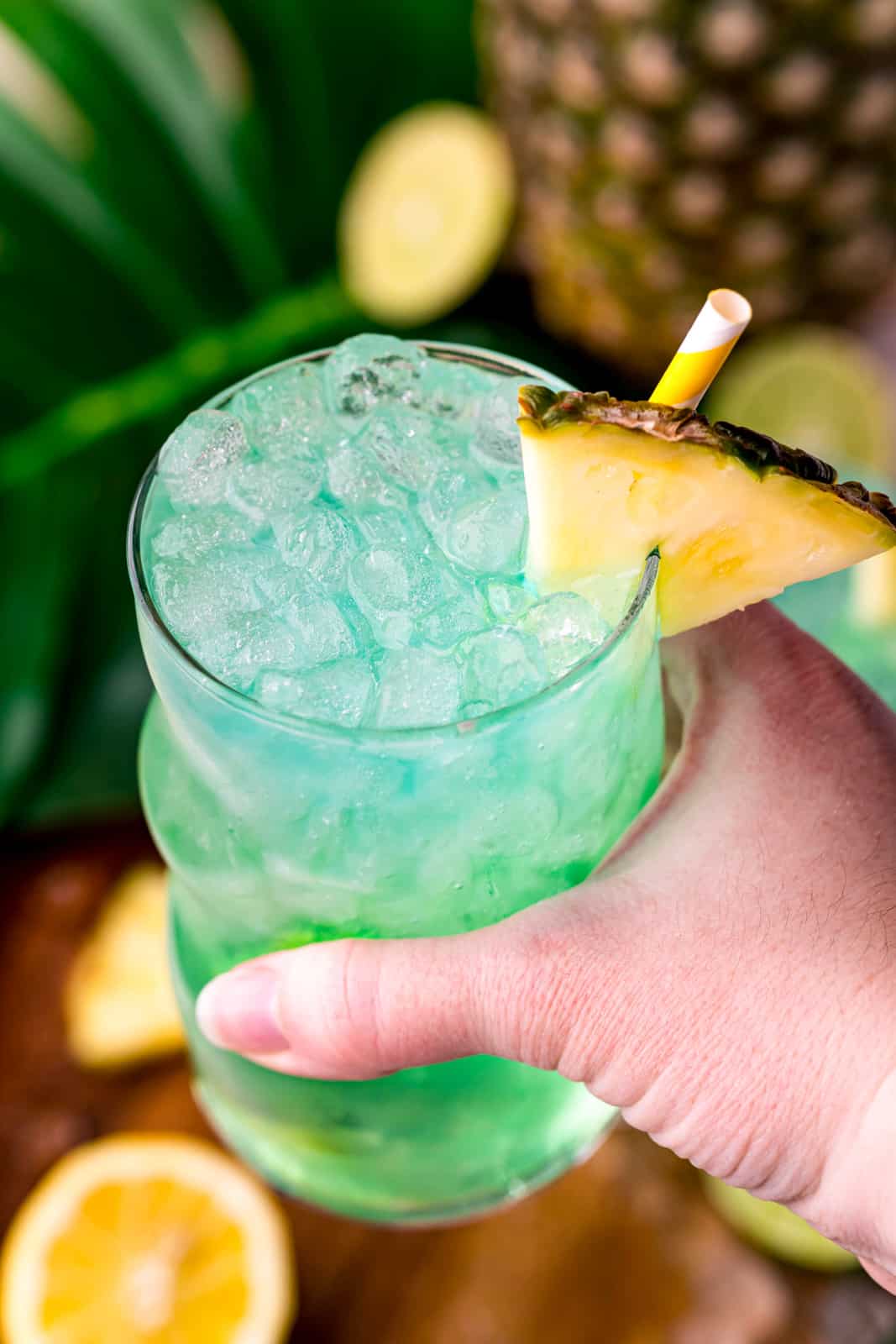 Hand holding up finished drink showing pineapple garnish