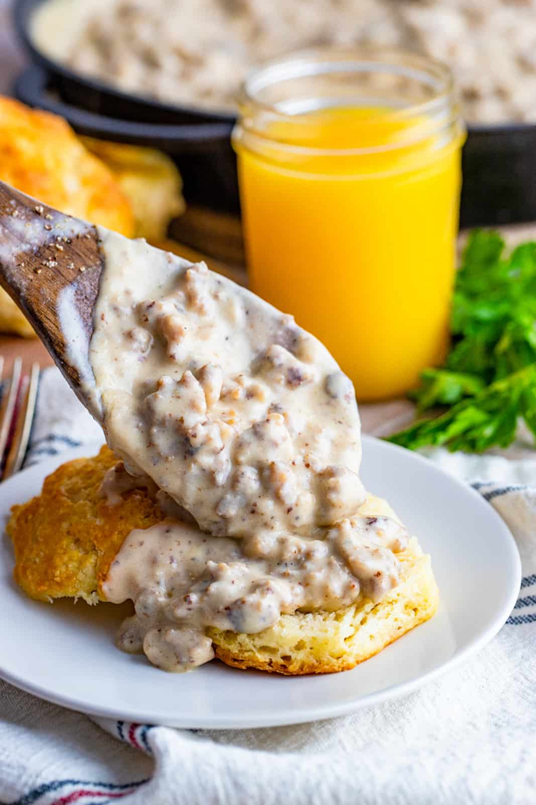 Spoon scooping Sausage Gravy over Biscuits