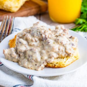 Square image of a Biscuits and Gravy Recipe on white plate topped with pepper