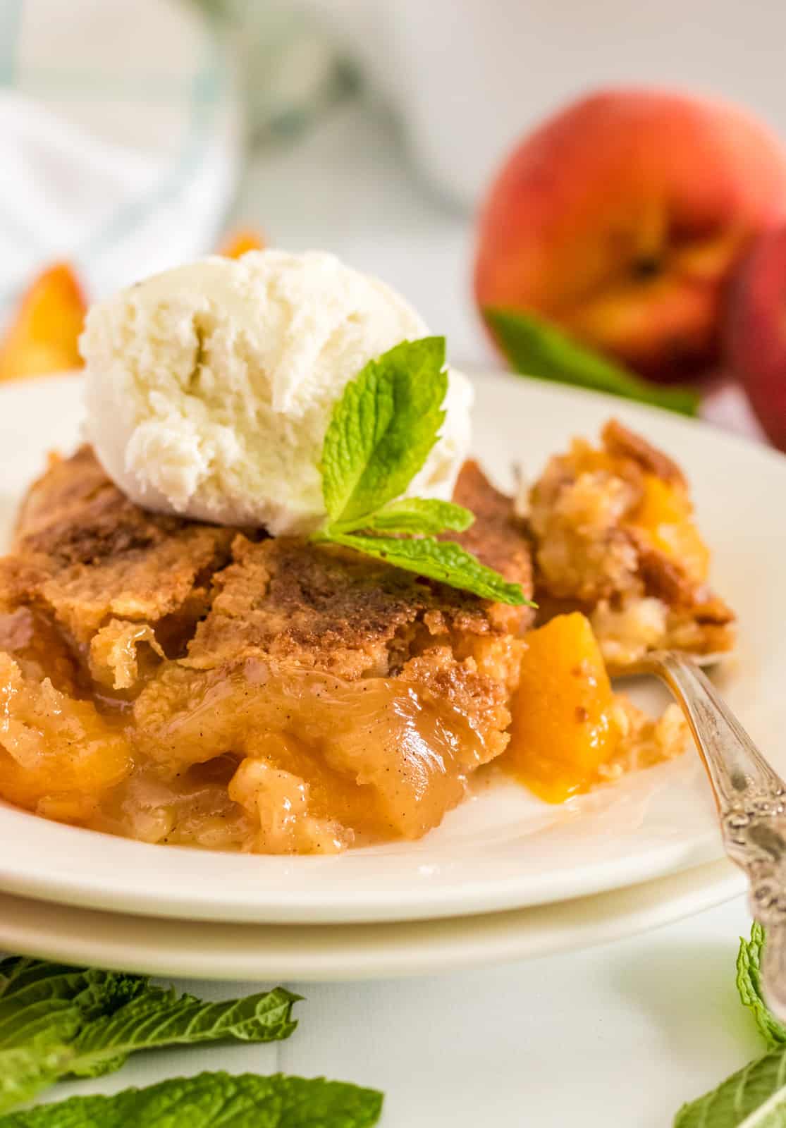Peach Dump Cake on two white plates topped with ice cream and mint
