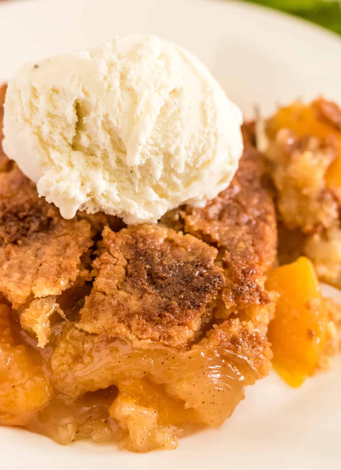 Close up of dump cake plate showing the cooked peaches and crispy cake topping