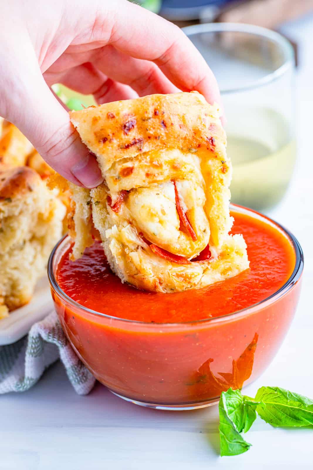 Hand dipping one Pepperoni Pizza Roll into marinara sauce
