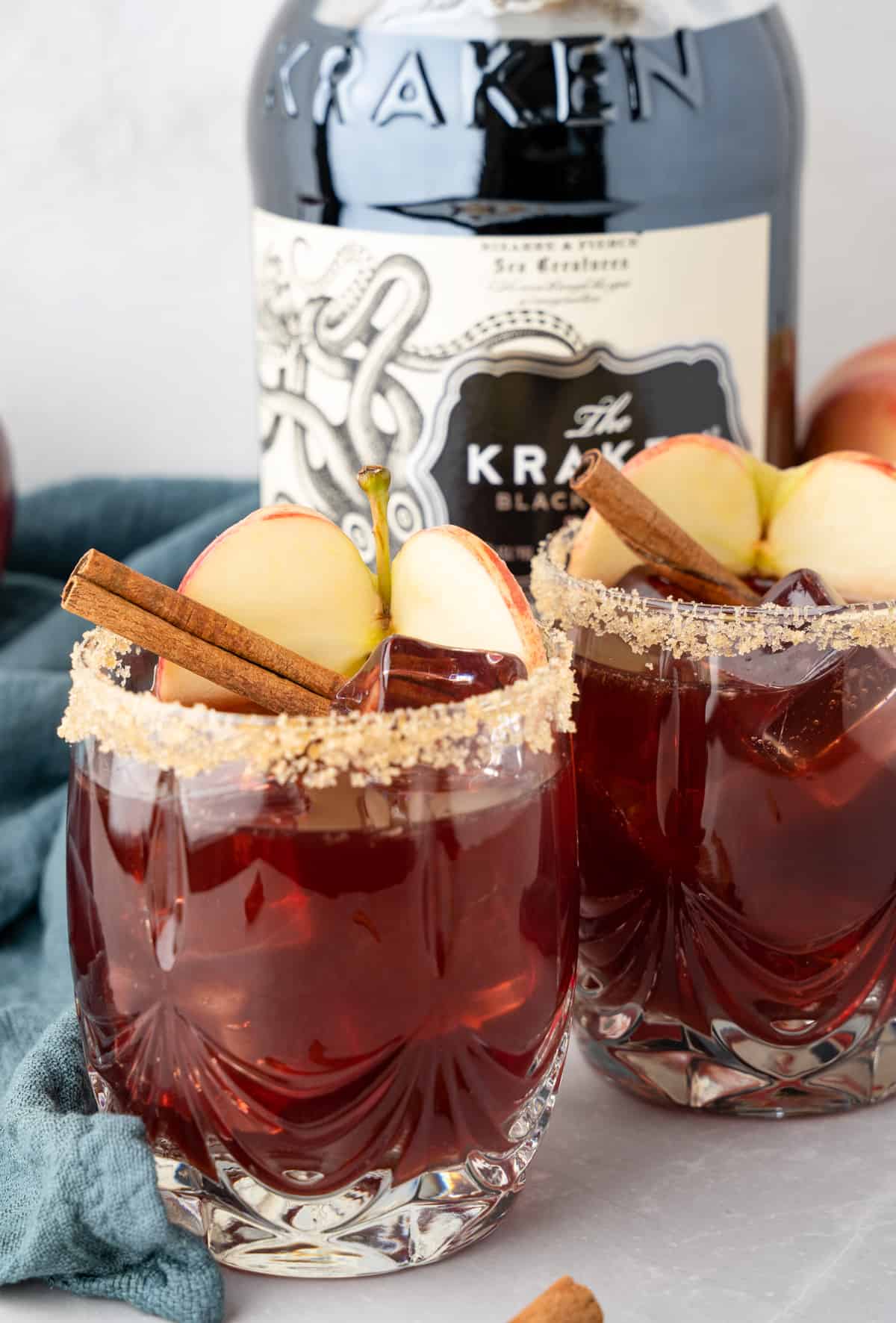 Two glasses of Apple Cider Sangria with brown sugar rim and garnished with sliced apple and cinnamon stick.