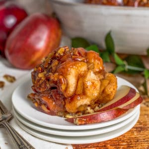 Square image of monkey bread on white plate with apples