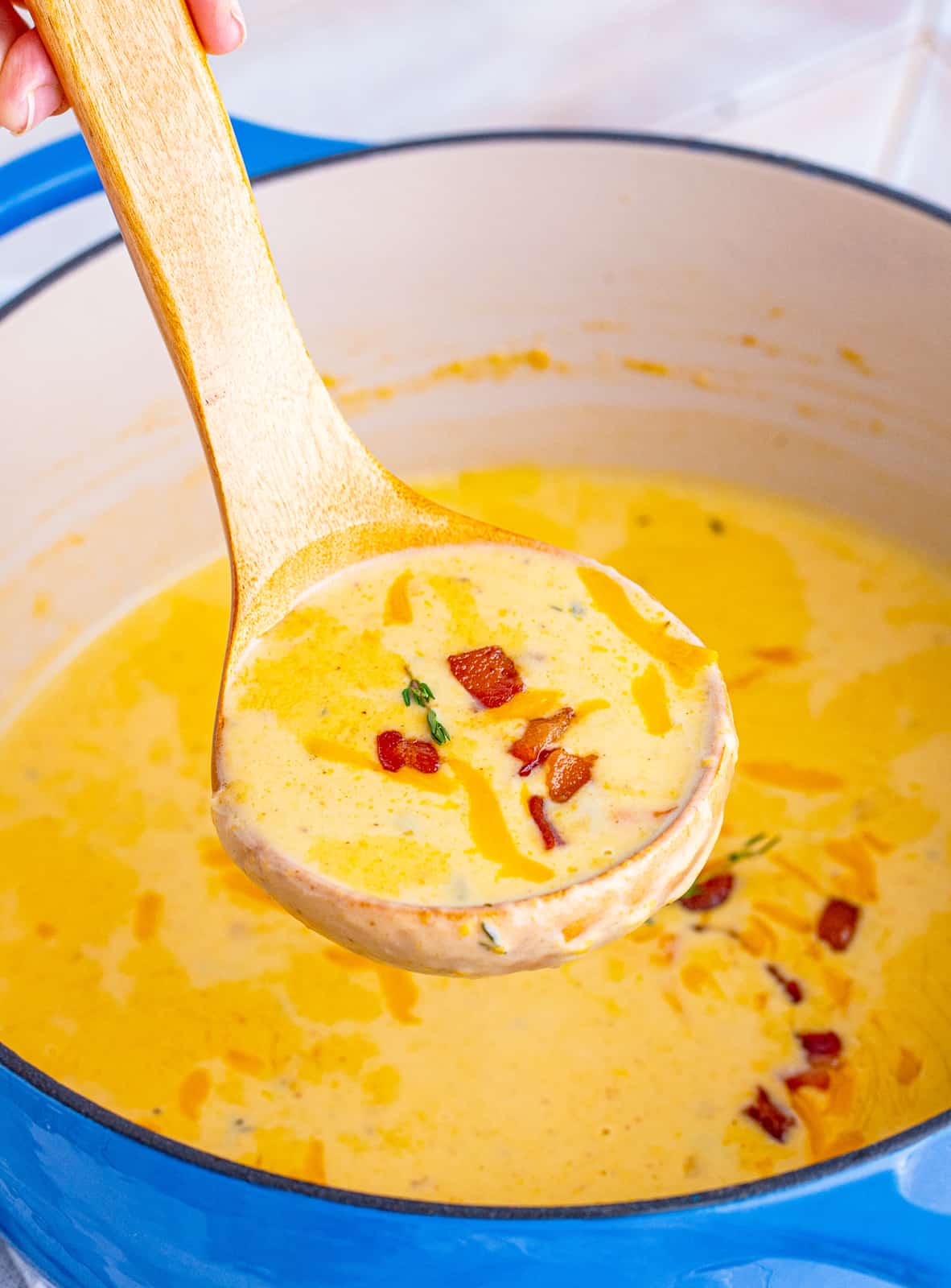 Beer Cheese Soup in ladle showing bacon.