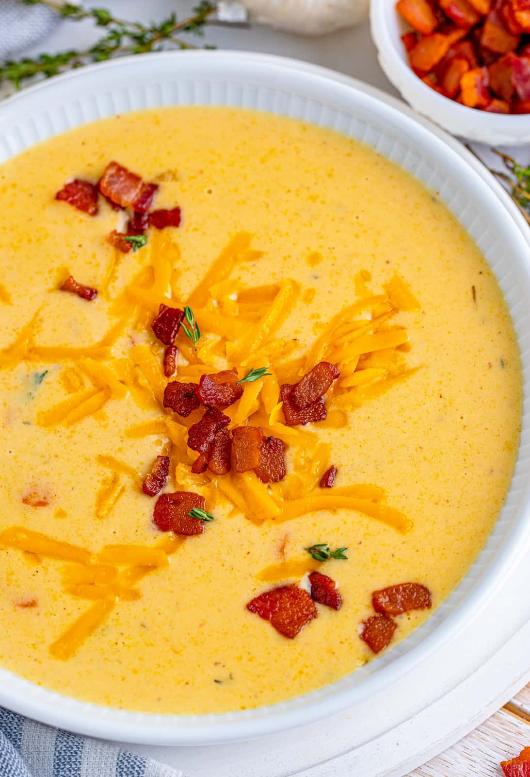 Overhead of Beer Cheese Soup in white bowl with bacon and cheese.
