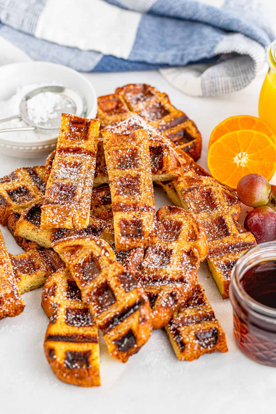 French Toast Waffle Stick Recipe with powdered sugar, syrup and oranges.