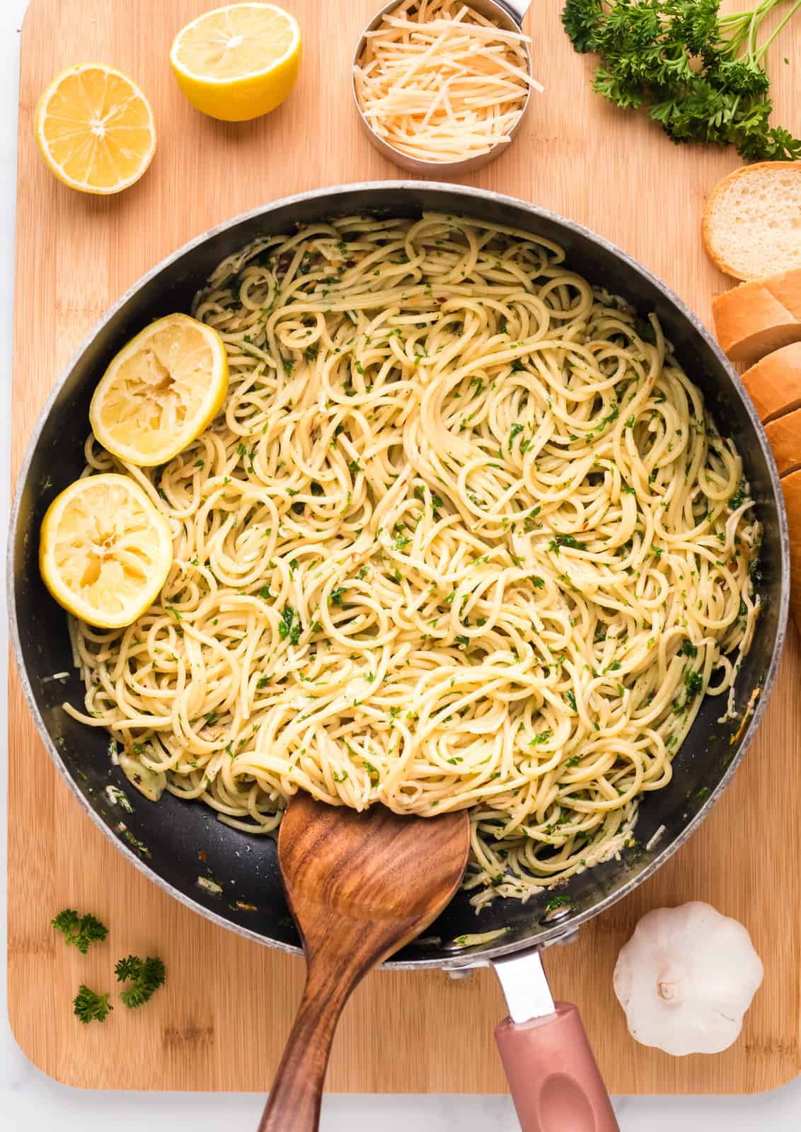 Spaghetti Aglio e Olio in pan with spoon and lemons.