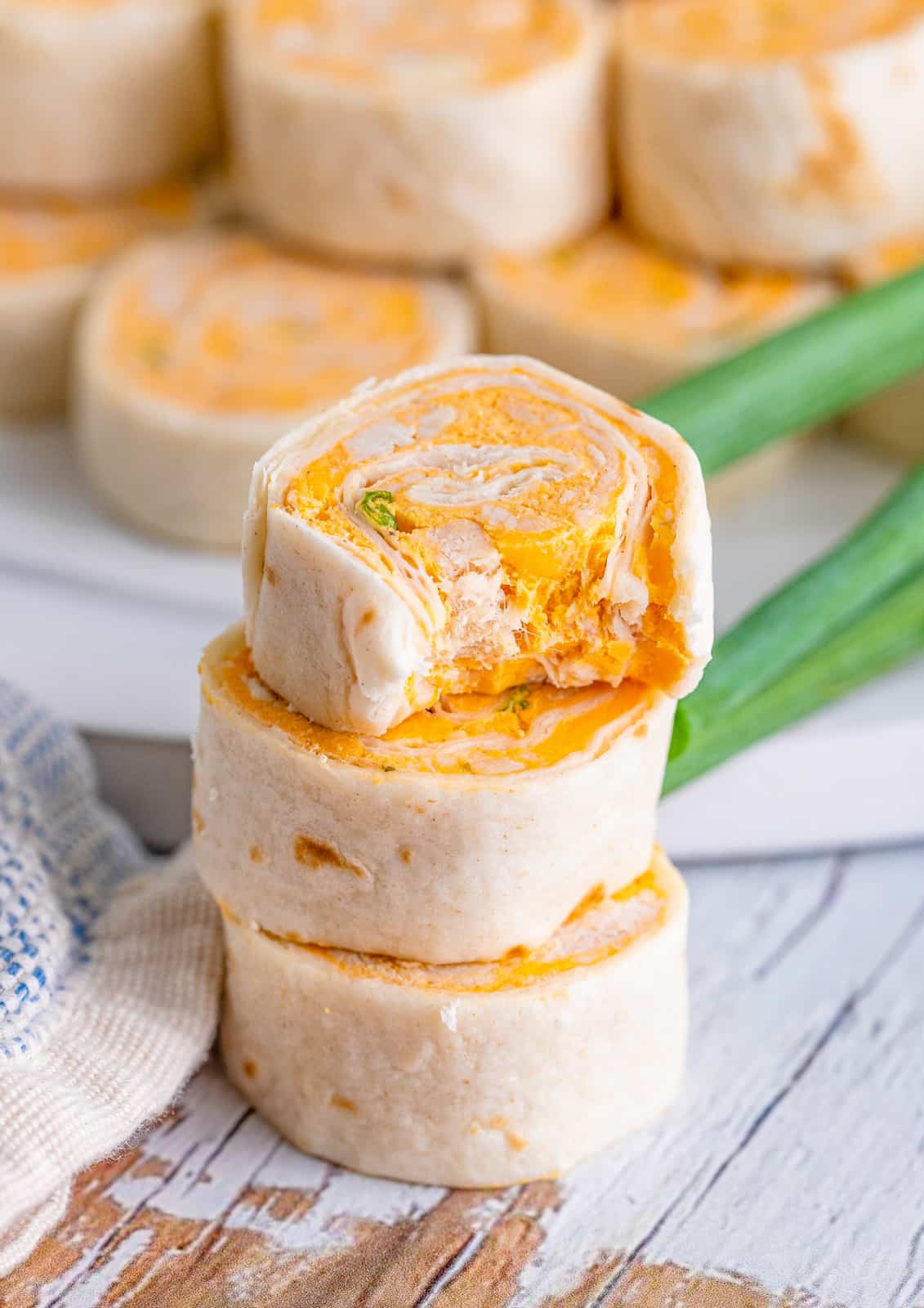 Three stacked Buffalo Chicken Pinwheels with bite taken out of top one.