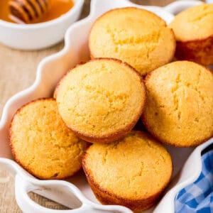 Close up square image of finished muffins in a scalloped white dish.