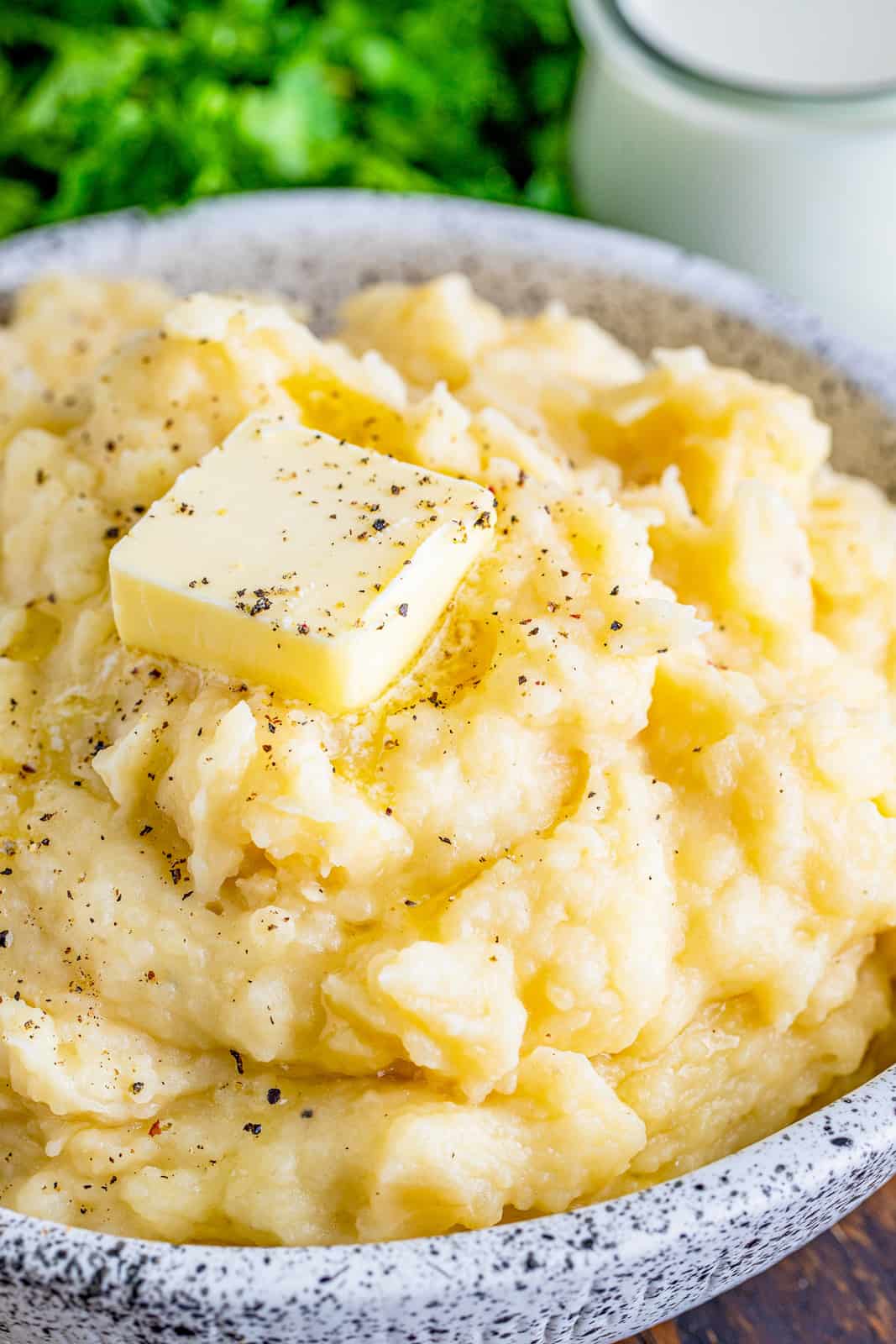 Close up of serving bowl filled with Crockpot Mashed Potatoes with butter on top.