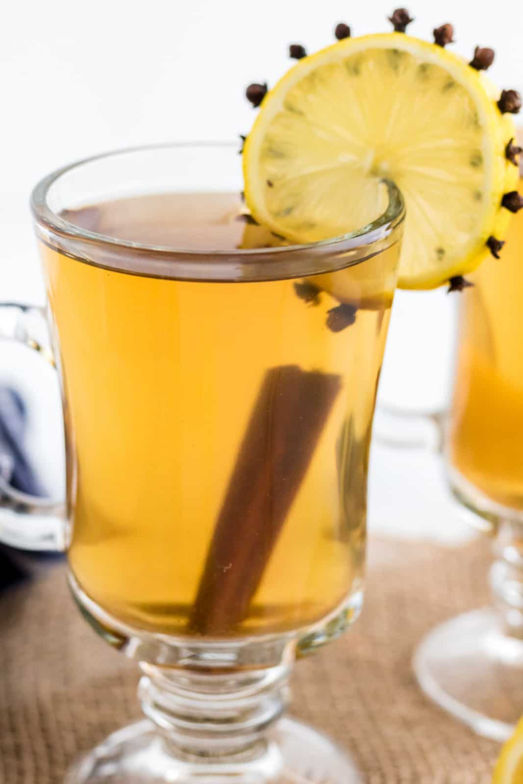 Close up of one glass full of Hot Toddy Recipe wth lemon slice and cinnamon stick.