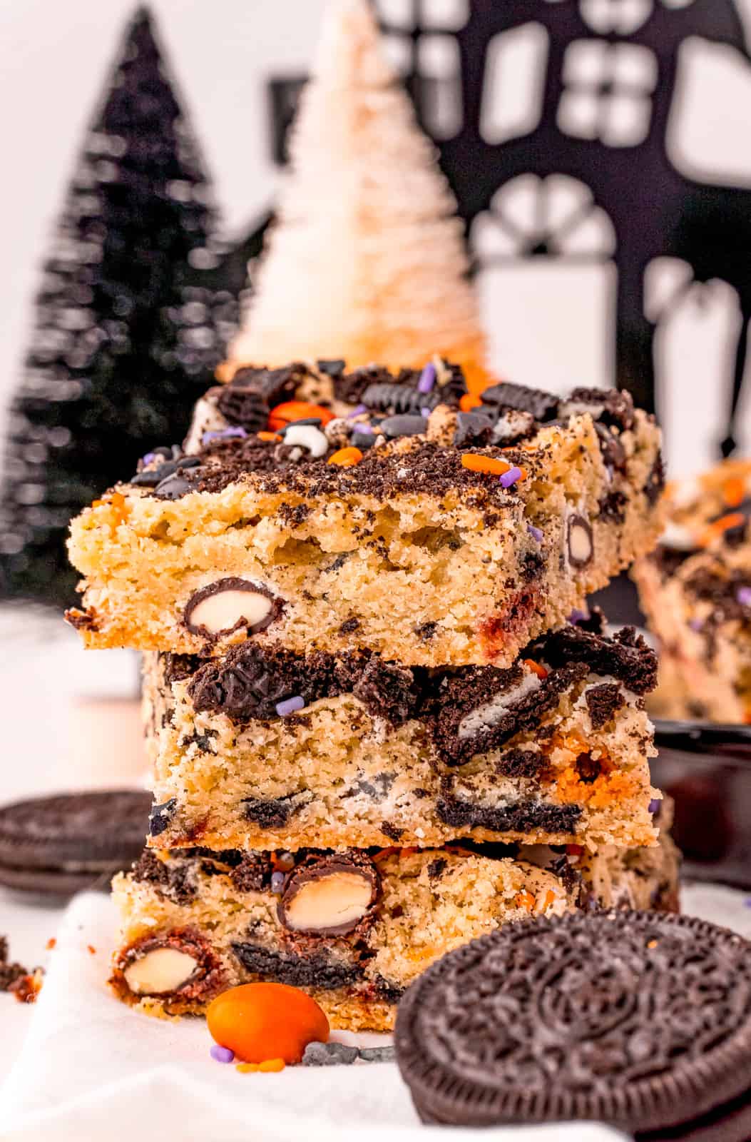 Three stacked Cookie Bars with Oreos and M&Ms around them.