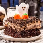 Square image of slice of Halloween Dirt Cake topped with pumpkins ahd ghost.
